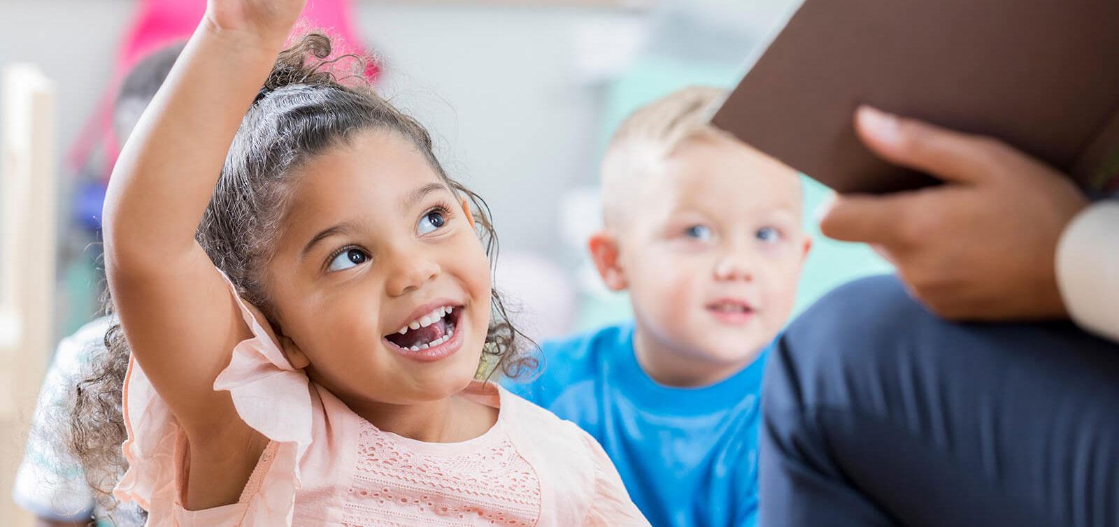 Girl raising her hand in preschool.