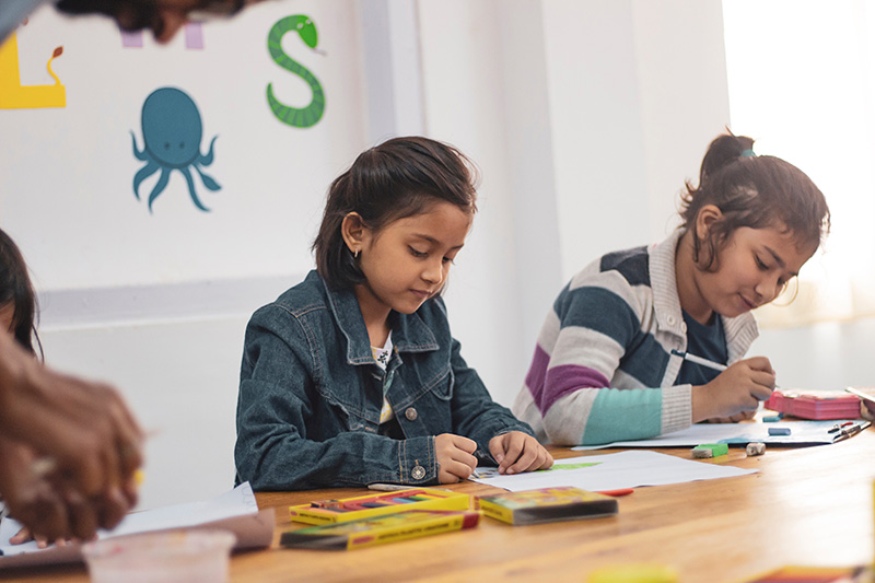 Two young girls work on projects in class.