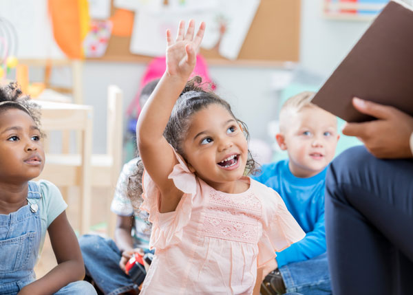 Child at daycare raising her hand