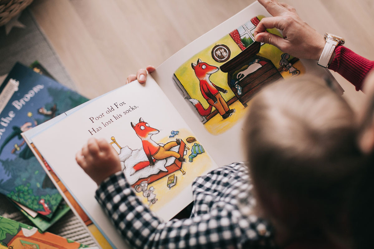 Child reading a picture book with a parent