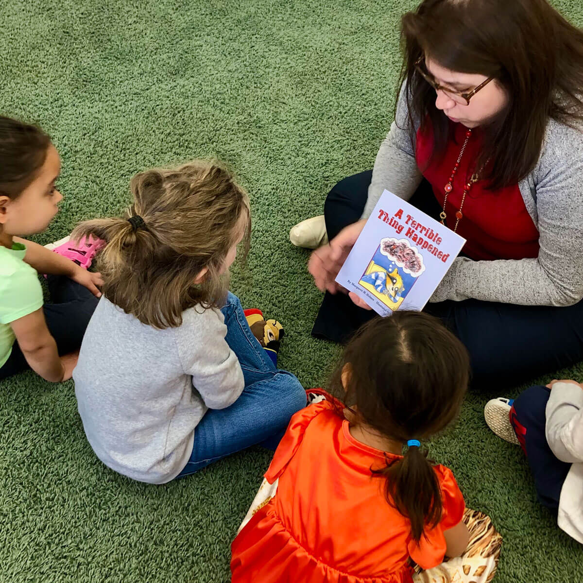 Childcare provider reading to a group of children.