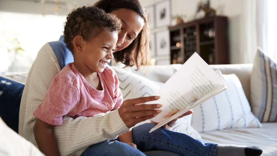 Caregiver and young child reading a book