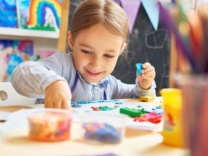 Child at table in childcare program with art supplies.