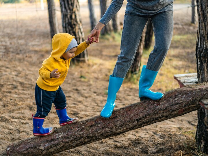 Caregiver and child stepping on a log