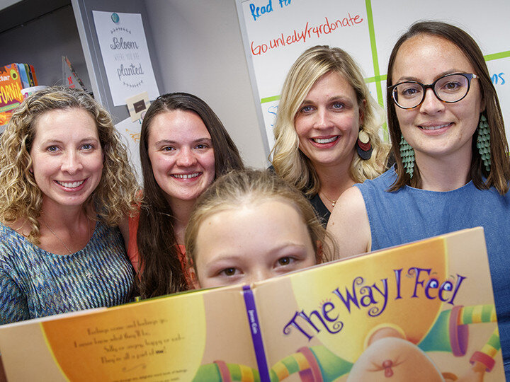 A group of individuals surrounding a book.