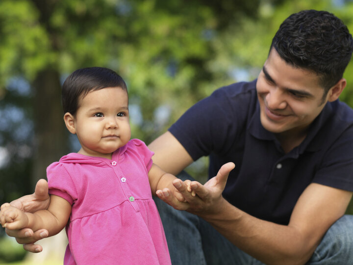 Father helping infant child walk