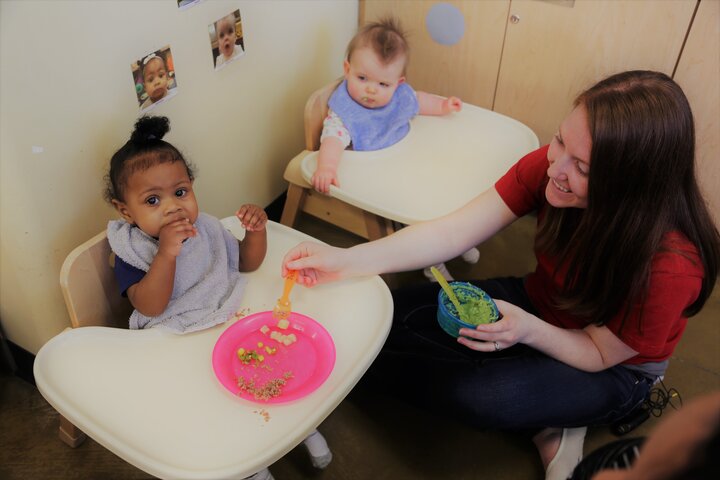 Caregiver feeding infants in floor highchairs