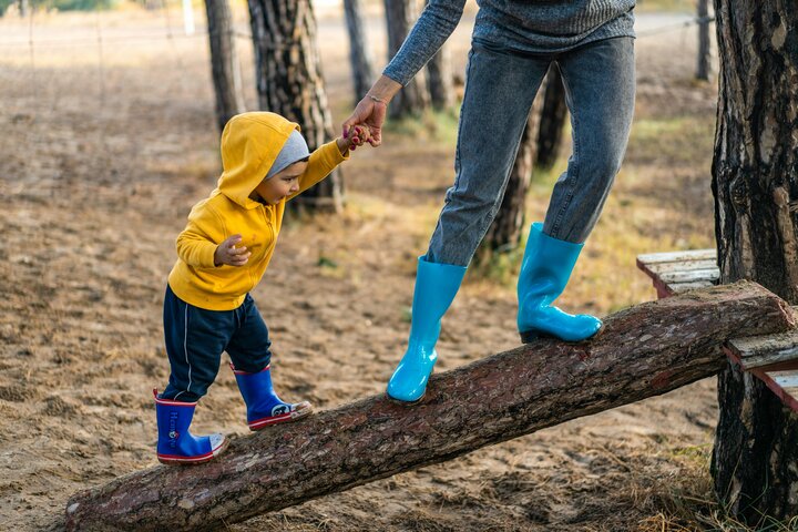 Caregiver and child stepping on a log