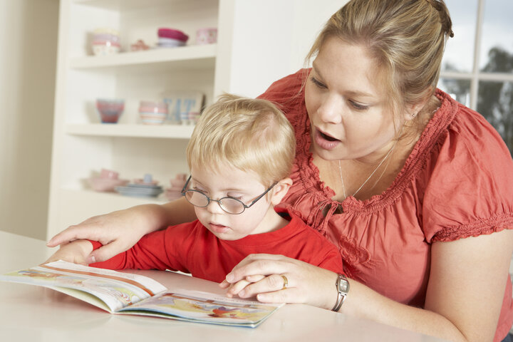 Caregiver and young child sitting with a book.