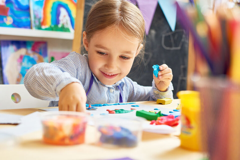 Child at table in childcare program with art supplies.